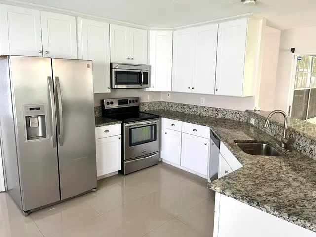 a kitchen with stainless steel appliances granite countertop a refrigerator sink and stove