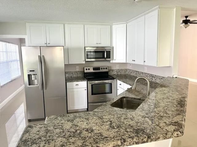 a kitchen with granite countertop a sink stove and cabinets
