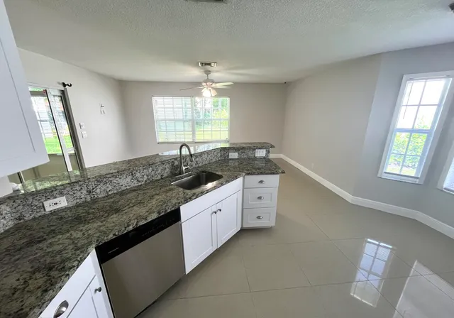 a kitchen with granite countertop white cabinets and a window