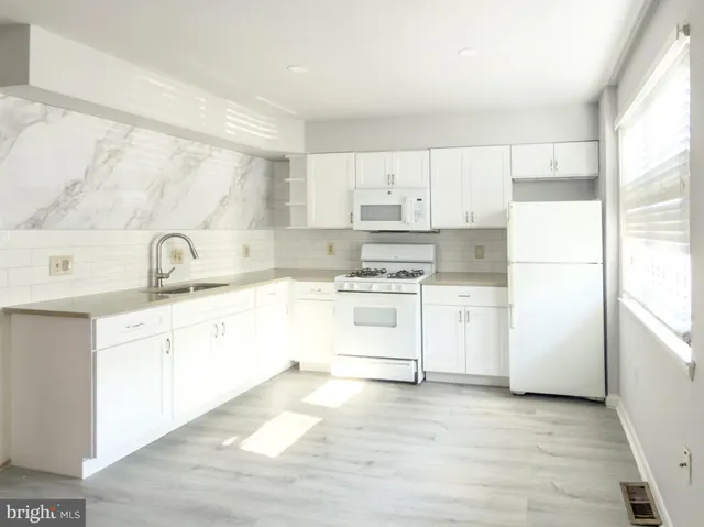 a kitchen with white cabinets and white appliances