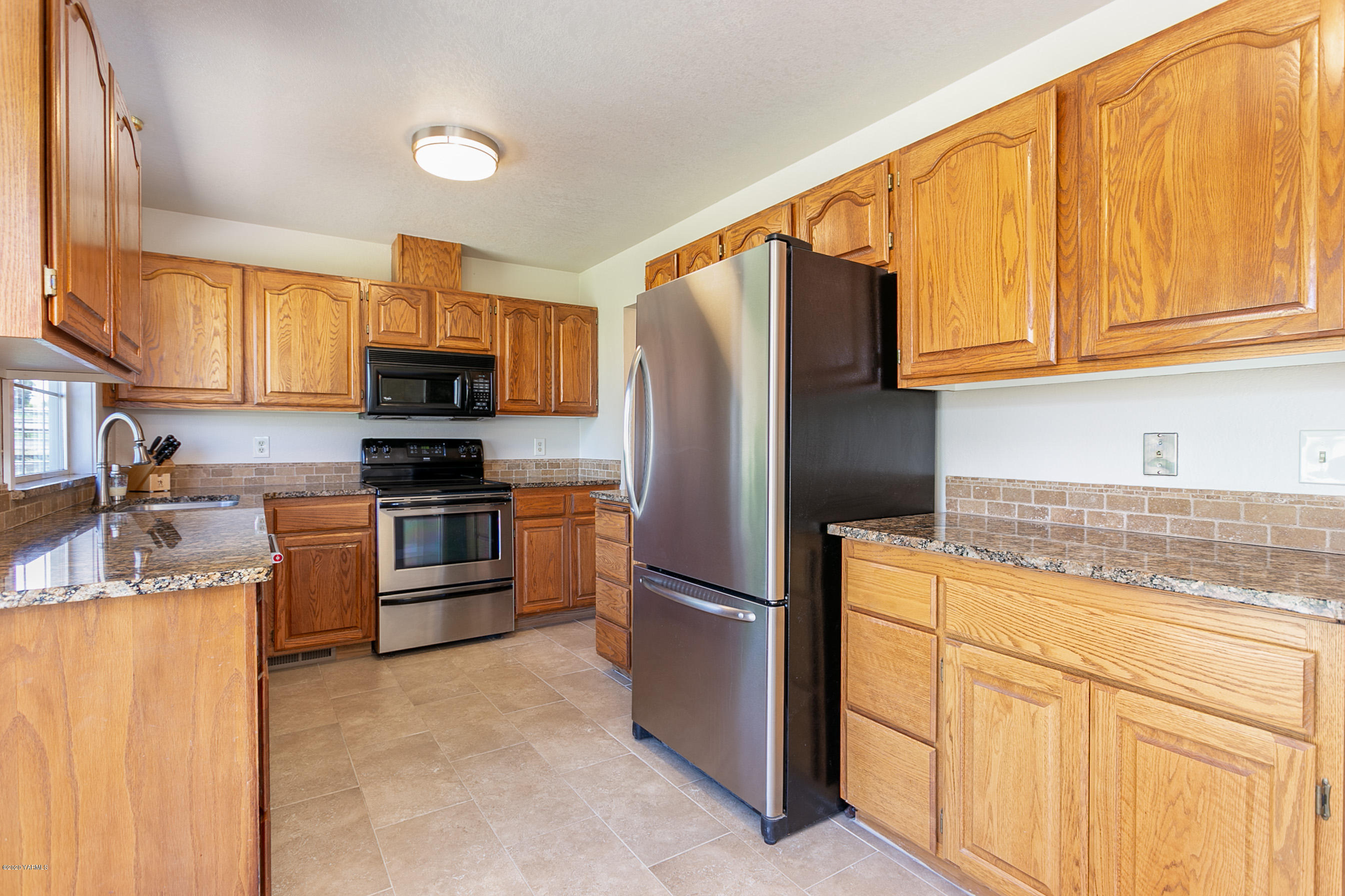 601 Brewer Road Grandview, WA 98930 - Photo 9 of 32 a kitchen with granite countertop white cabinets and stainless steel appliances