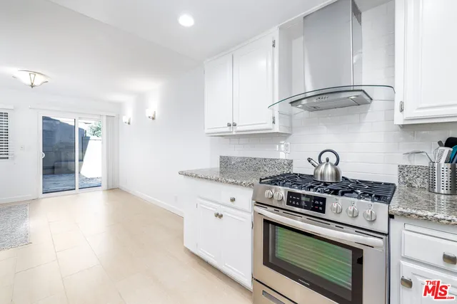 a kitchen with stainless steel appliances granite countertop white cabinets and a stove top oven