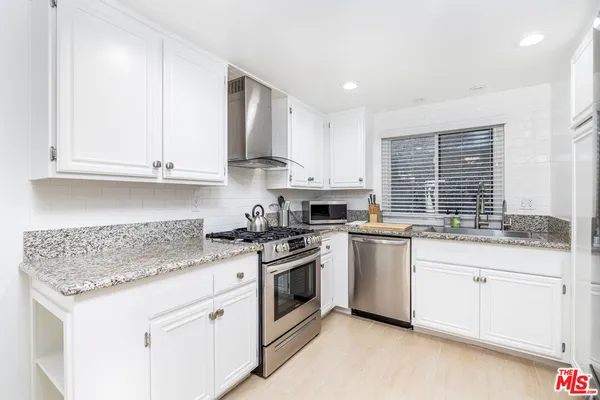 a kitchen with stainless steel appliances granite countertop a sink stove and cabinets