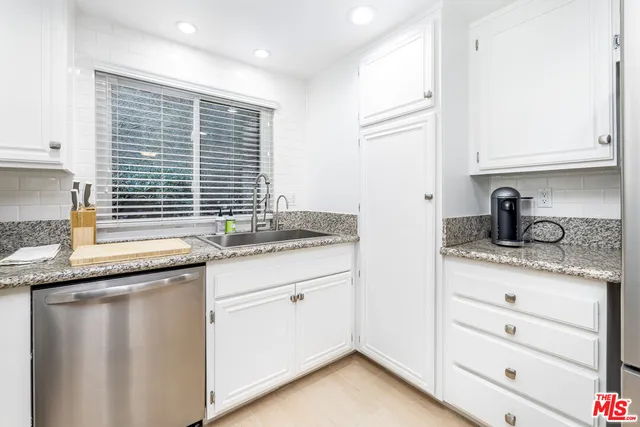 a kitchen with granite countertop cabinets stainless steel appliances and a sink