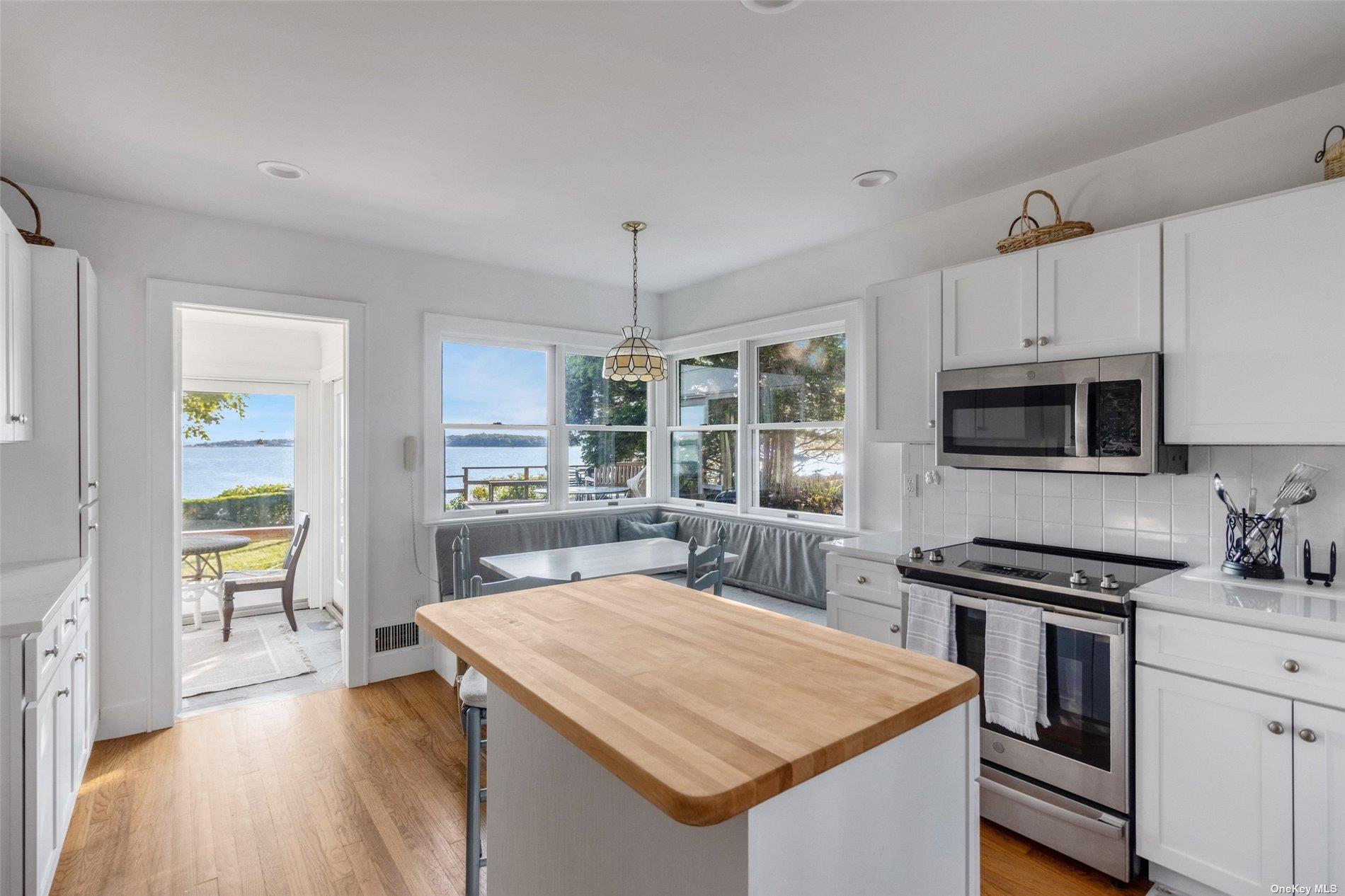 930 West Cove Road Cutchogue, NY 11935 - Photo 11 of 34 a kitchen with stainless steel appliances a kitchen island hardwood floor sink stove dining table and chairs
