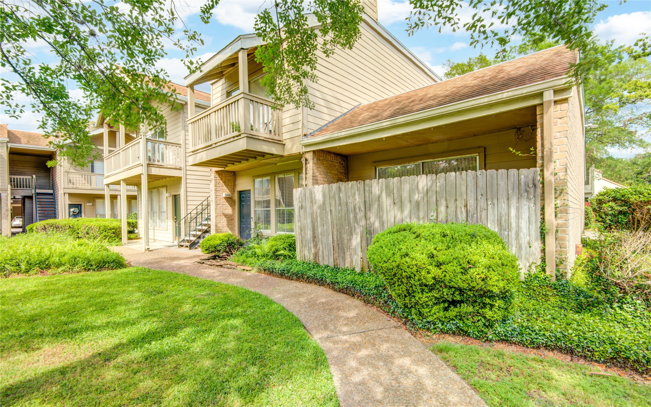 2100 Tanglewilde Street, Unit 349 Houston, TX 77063 - Photo 2 of 29 a view of a brick house with a large windows plants and large trees