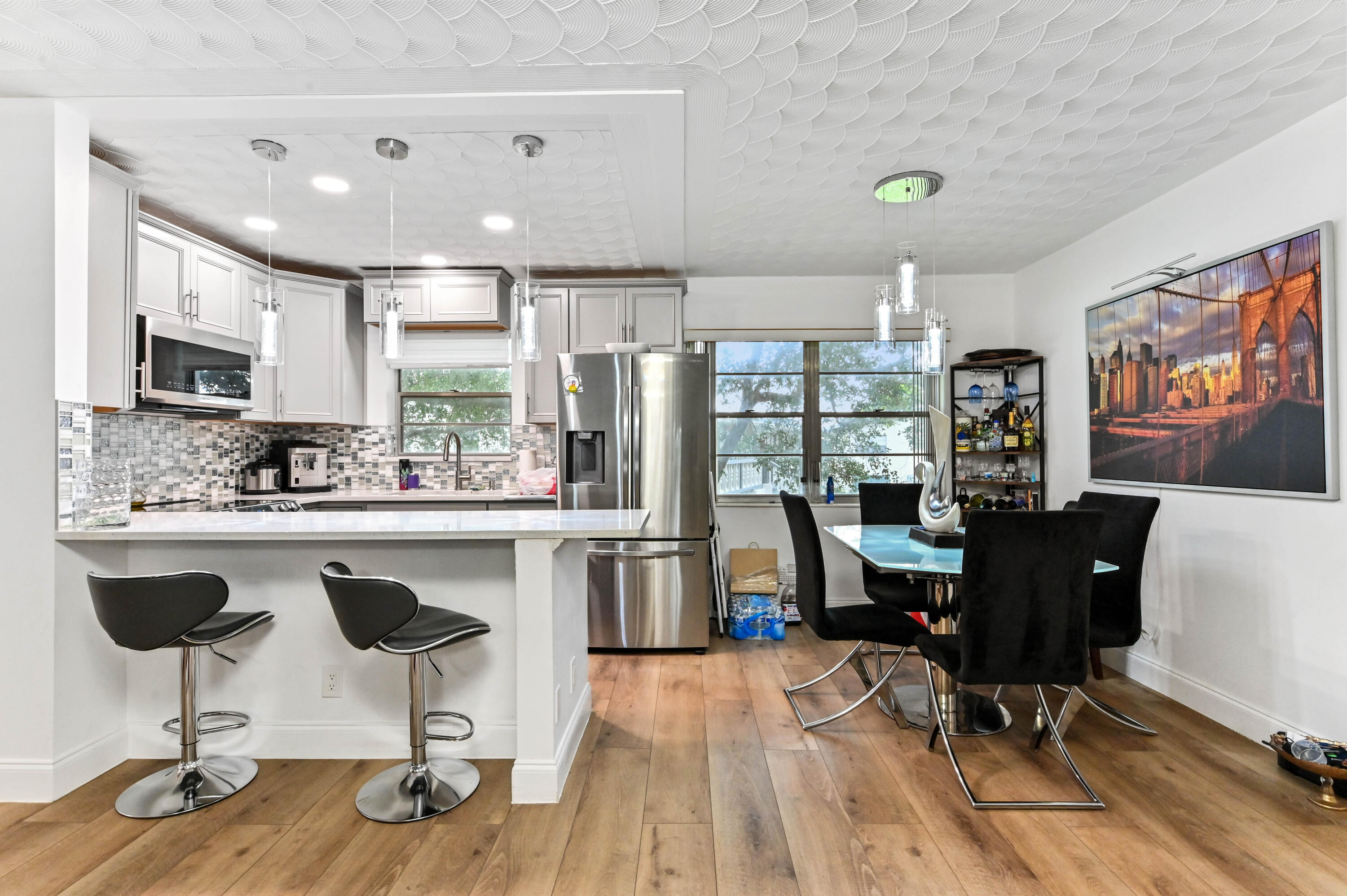 204 Ellesmere D Deerfield Beach, FL 33442 - Photo 5 of 46 a open kitchen with stainless steel appliances granite countertop a stove a refrigerator a sink dishwasher a dining table and chairs with wooden floor