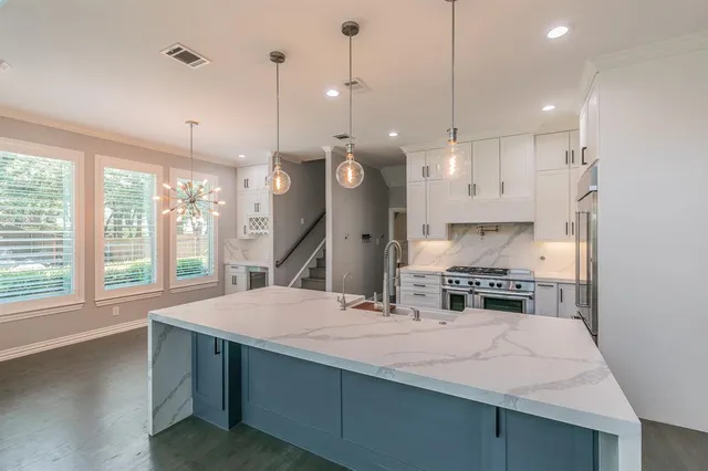 a large kitchen with kitchen island a large counter space a sink appliances and a large window