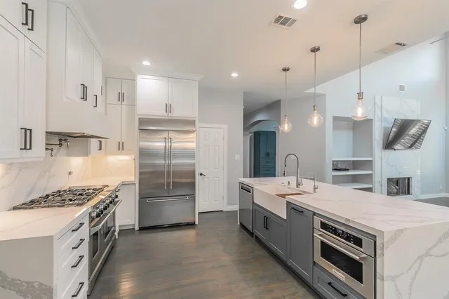 a large kitchen with stainless steel appliances kitchen island a stove a sink a refrigerator and a cabinets