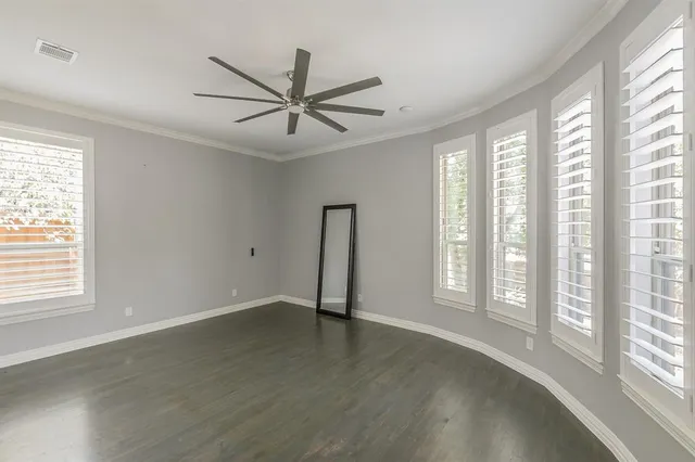 a view of an empty room with a window and wooden floor