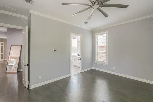 an empty room with wooden floor closet and windows