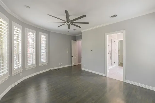an empty room with wooden floor fan and windows