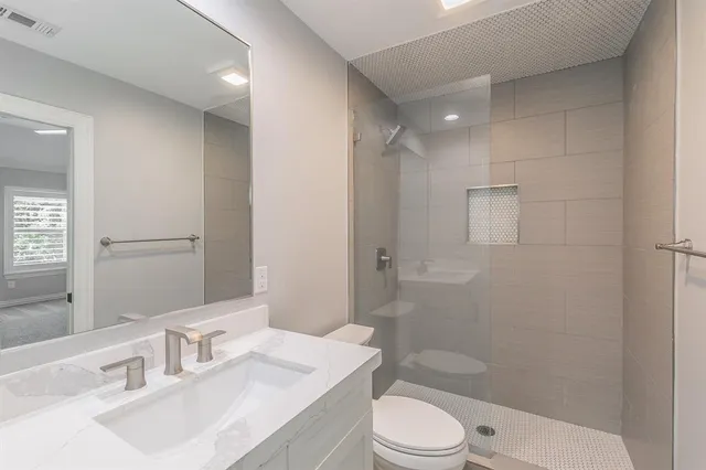 a bathroom with a sink a toilet a mirror and shower