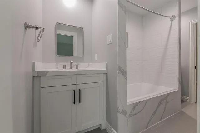a bathroom with a bathtub sink vanity and mirror