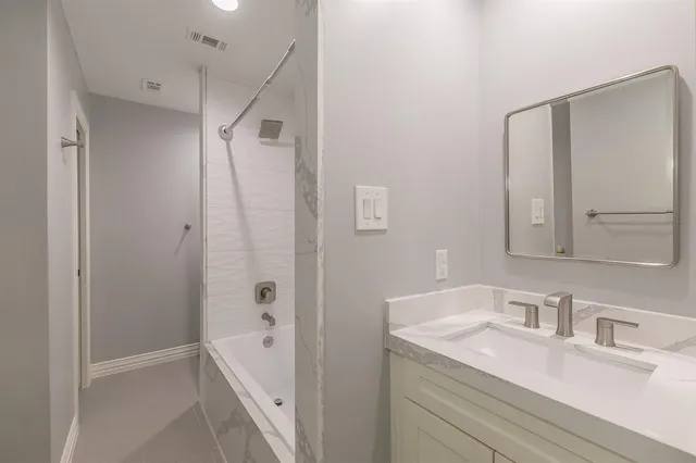 a bathroom with a granite countertop sink a mirror and a bathtub