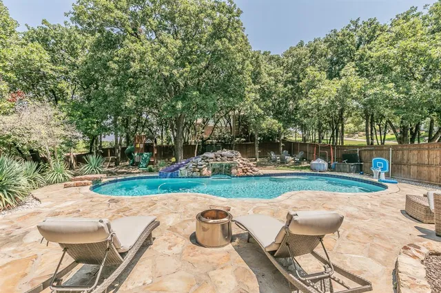 a view of a backyard with table and chairs potted plants and large tree