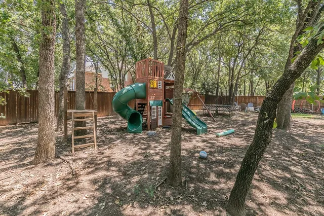 a view of a house with a backyard space and a large tree