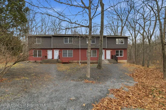 a front view of a house with large trees