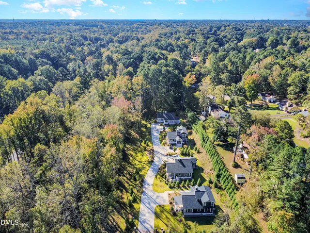 a view of a big house with a big yard plants and large trees
