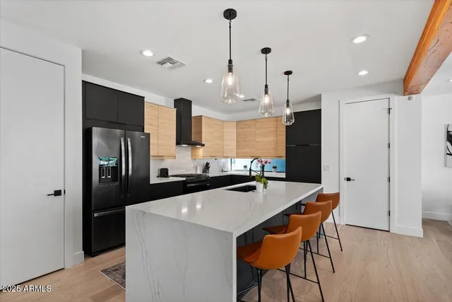 a kitchen with stainless steel appliances kitchen island a table chairs in it and wooden floors