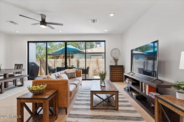 a living room with furniture a flat screen tv and a floor to ceiling window