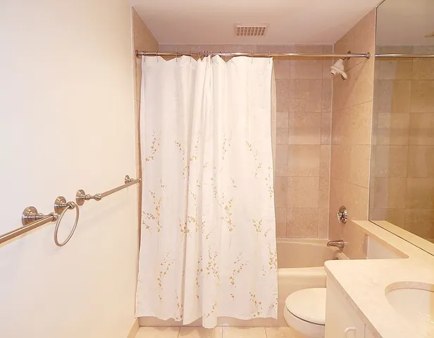 a bathroom with a shower curtain a mirror and a toilet