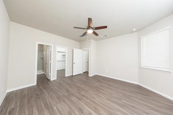a view of an empty room with window and wooden floor