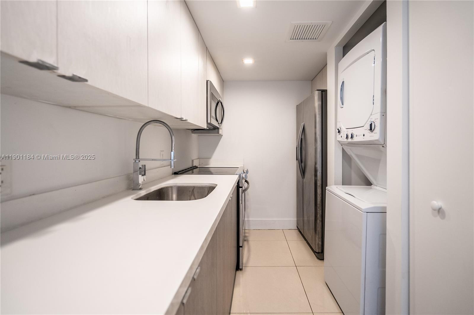 1985 Bay Drive, Unit 111 Miami Beach, FL 33141 - Photo 7 of 20 a kitchen with a sink a refrigerator and cabinets