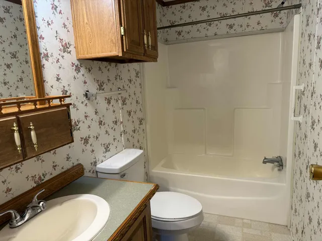 a bathroom with a granite countertop toilet sink and mirror