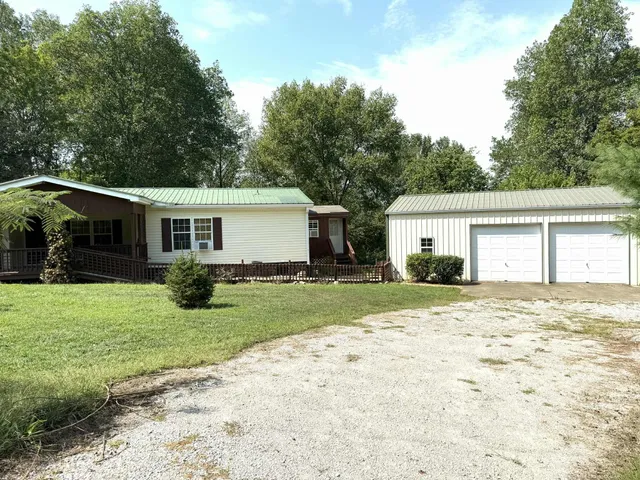 a view of a house with a yard and large tree