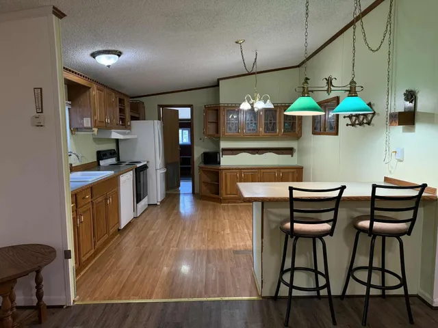 a kitchen with stainless steel appliances kitchen island granite countertop a table chairs in it and wooden floors