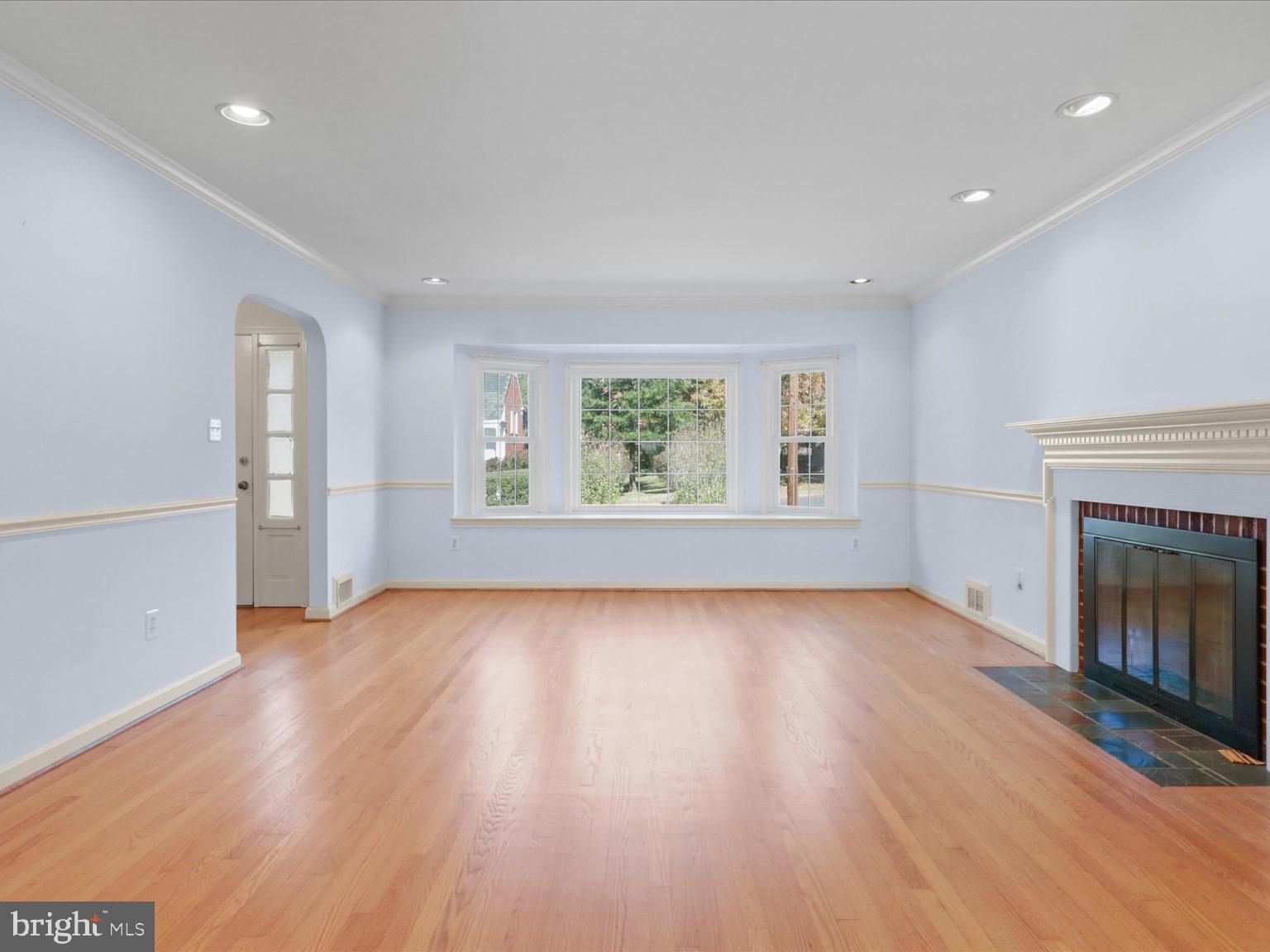 1002 Beverley Drive Alexandria, VA 22302 - Photo 6 of 46 an empty room with wooden floor fireplace and windows