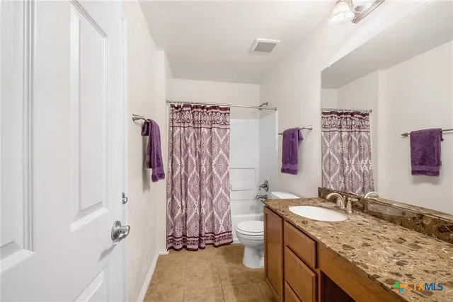a bathroom with a granite countertop sink and a shower curtain