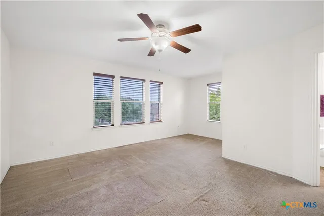 an empty room with windows and ceiling fan