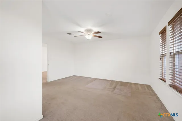 an empty room with windows and ceiling fan