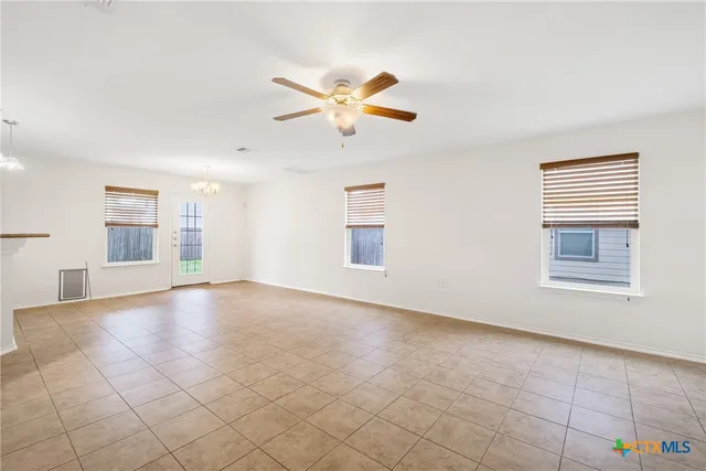 an empty room with windows and fan