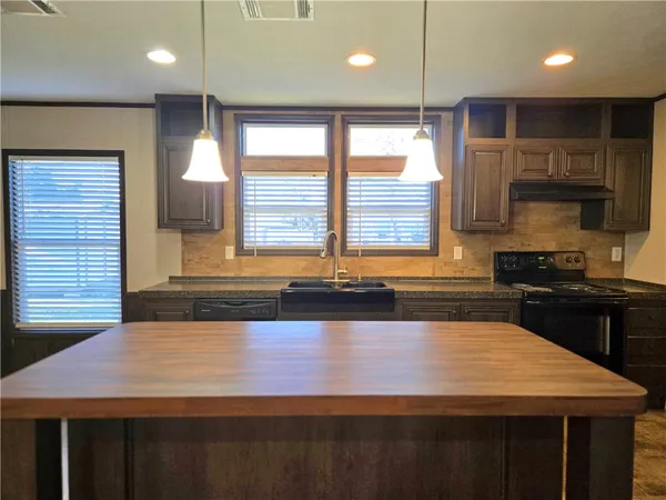 a view of a kitchen with kitchen island a sink wooden floor and a counter top space