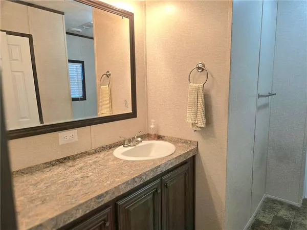 a bathroom with a granite countertop sink and a mirror