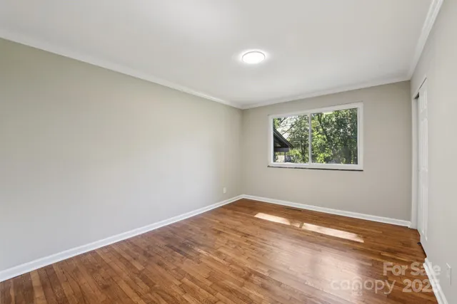 an empty room with wooden floor and window