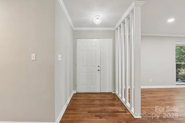 a view of a hallway with wooden floor and a bathroom