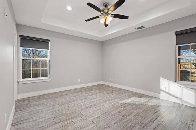 an empty room with wooden floor and windows