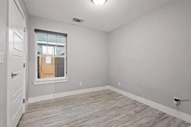 a view of an empty room with wooden floor and a window