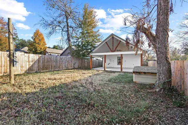 a front view of a house with a yard and a large tree