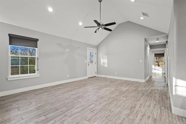 an empty room with wooden floor closet and windows