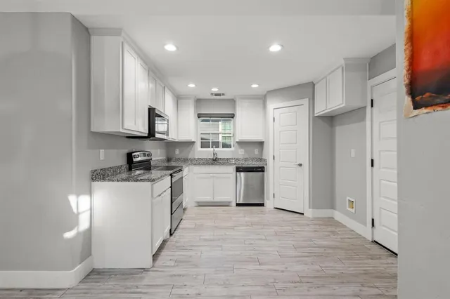 a kitchen with stainless steel appliances granite countertop a refrigerator sink and white cabinets