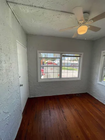 an empty room with wooden floor and windows