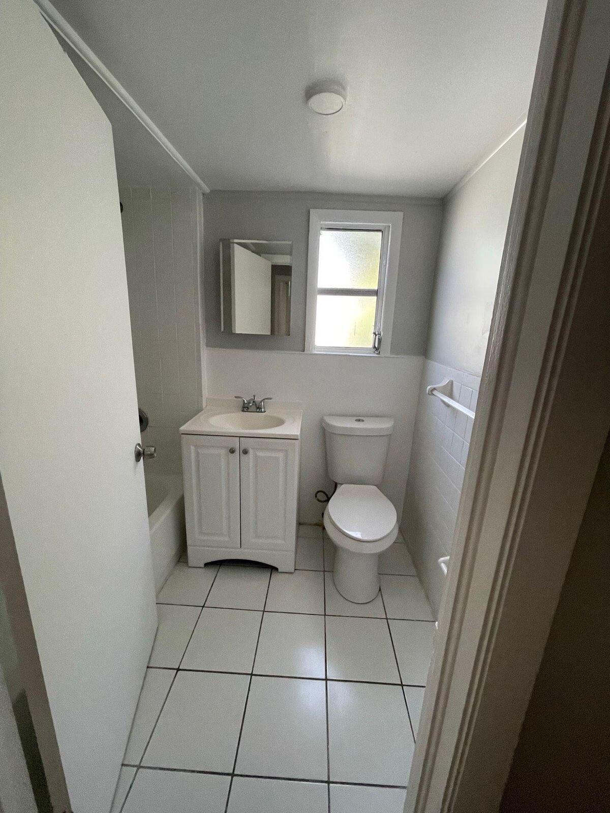 736 Omar Road, Unit 1 West Palm Beach, FL 33405 - Photo 18 of 25 a bathroom with a toilet a sink a mirror and a window