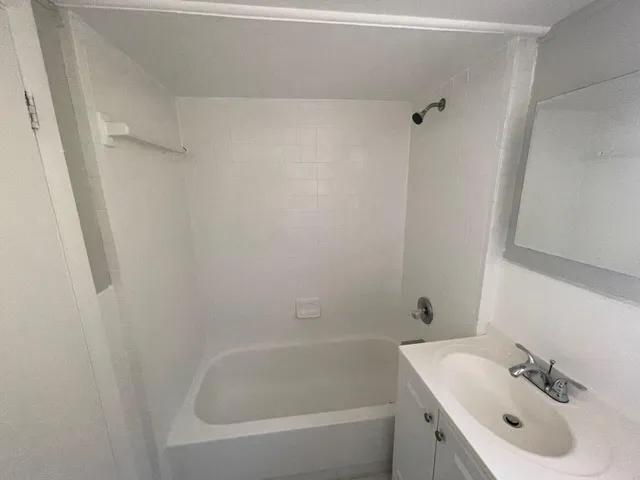 a white bath tub sitting next to a white sink and vanity