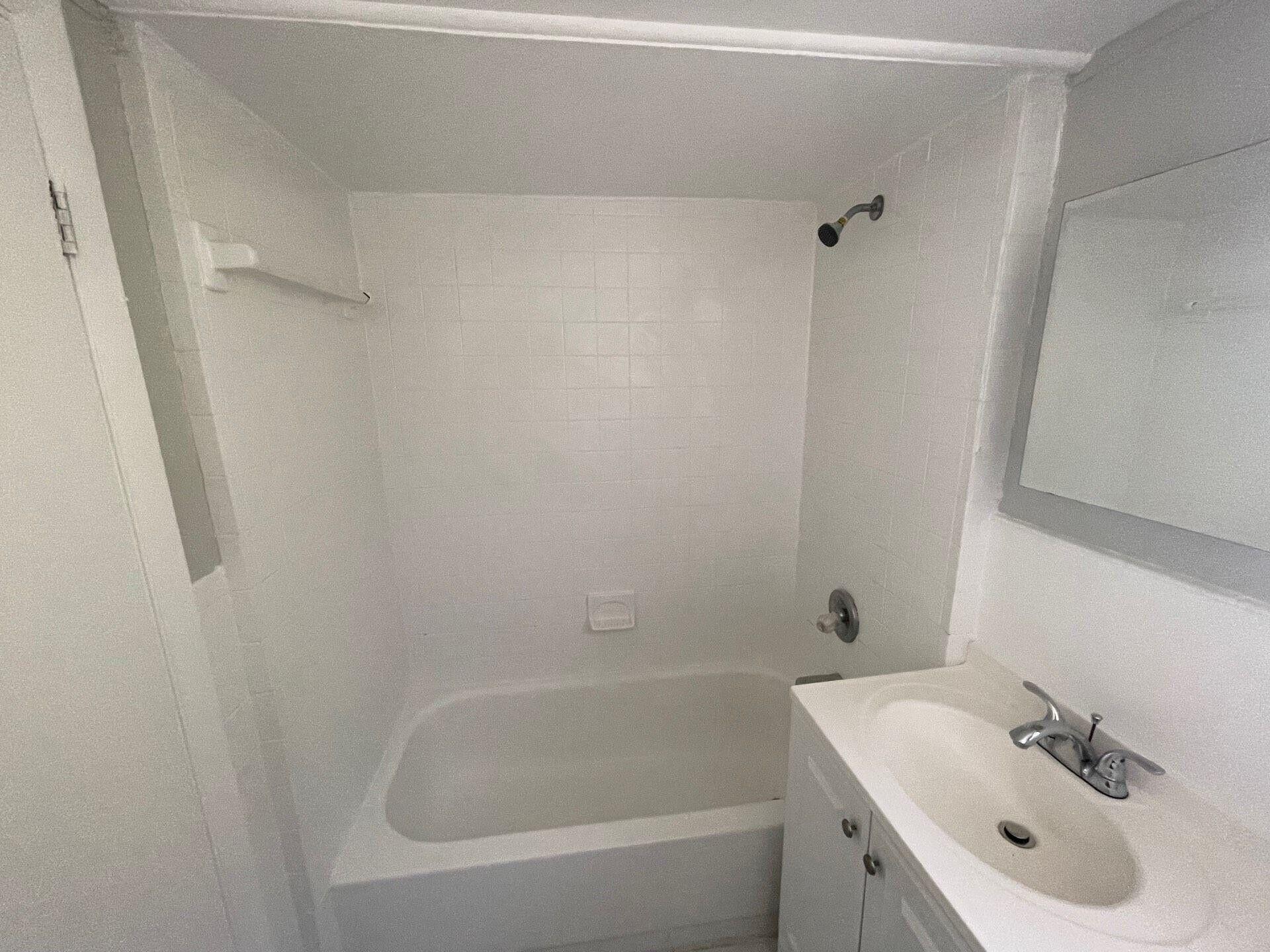 736 Omar Road, Unit 1 West Palm Beach, FL 33405 - Photo 19 of 25 a white bath tub sitting next to a white sink and vanity