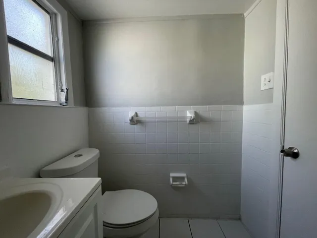 a white toilet sitting next to a window and a sink